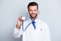 Young handsome smiling medic in white coat holding stethoscope