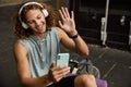 Young handsome smiling sporty long-haired man in headphones with phone Royalty Free Stock Photo