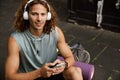 Young handsome smiling sporty long-haired man in headphones with phone Royalty Free Stock Photo