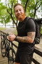 Young handsome smiling tattooed bearded man holding his phone