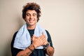 Young handsome sportsman wearing towel standing over isolated white background smiling with hands on chest with closed eyes and Royalty Free Stock Photo