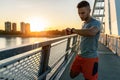 Young handsome sporty jogger taking break from exercising outdoors looking on a smart fitness watch