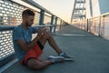 Young handsome sporty jogger taking break from exercising outdoors looking on a smart fitness watch