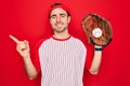 Young handsome sporty man with blue eyes playing baseball using glove and ball very happy pointing with hand and finger to the Royalty Free Stock Photo