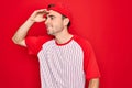 Young handsome sporty man with blue eyes wearing striped baseball t-shirt and cap very happy and smiling looking far away with Royalty Free Stock Photo