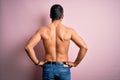 Young handsome strong man with beard shirtless standing over isolated pink background standing backwards looking away with arms on Royalty Free Stock Photo
