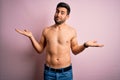 Young handsome strong man with beard shirtless standing over isolated pink background clueless and confused expression with arms Royalty Free Stock Photo