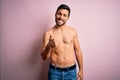 Young handsome strong man with beard shirtless standing over isolated pink background doing happy thumbs up gesture with hand Royalty Free Stock Photo