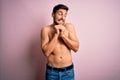 Young handsome strong man with beard shirtless standing over isolated pink background laughing nervous and excited with hands on