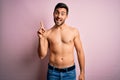 Young handsome strong man with beard shirtless standing over isolated pink background pointing finger up with successful idea Royalty Free Stock Photo