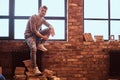 A young handsome student with stylish beard and hair is sitting on the windowsill in the college library Royalty Free Stock Photo