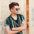 Young handsome stylish guy with sunglasses points in fashionable Royalty Free Stock Photo