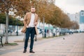 Young handsome stylish man wiyh beard in elegant coat standing in autumn park Royalty Free Stock Photo