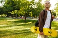 Young handsome stylish smiling boy with skateboard looking aside Royalty Free Stock Photo