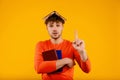 Young handsome surprised man with book on his head, points with finger up prepares for exams, on yellow background