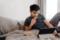 Young handsome thoughtful indian man liying on bed with tablet Royalty Free Stock Photo