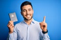 Young handsome tourist man holding australia australian passport id over blue background surprised with an idea or question