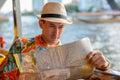 Young handsome tourist man reading map and riding boat on the river