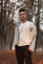 Young handsome trendy young man in a fashionable white t-shirt in a stylish blue denim jacket with a hairstyle posing in autumn Royalty Free Stock Photo