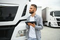 Young handsome truck driver is standing with a tablet near the truck Royalty Free Stock Photo