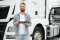 Young handsome truck driver is standing with a tablet near the truck Royalty Free Stock Photo