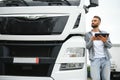 Young handsome truck driver is standing with a tablet near the truck Royalty Free Stock Photo