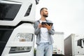 Young handsome truck driver is standing with a tablet near the truck Royalty Free Stock Photo