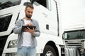 Young handsome truck driver is standing with a tablet near the truck Royalty Free Stock Photo