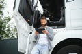 Young handsome truck driver is standing with a tablet near the truck Royalty Free Stock Photo