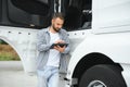 Young handsome truck driver is standing with a tablet near the truck Royalty Free Stock Photo