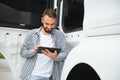 Young handsome truck driver is standing with a tablet near the truck Royalty Free Stock Photo