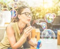 Young handsome woman blowing soap bubble in city bar with back sun light - Portrait of happy girl having fun outdoor - Happiness Royalty Free Stock Photo