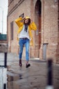 A young handsome woman in a yellow raincoat is enjoying rain drops while walking the city on a rainy day. Walk, rain, city Royalty Free Stock Photo