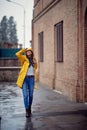 A young handsome woman in a yellow raincoat is enjoying a rain while walking the city. Walk, rain, city Royalty Free Stock Photo