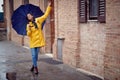 A young handsome woman in a yellow raincoat and with umbrella is dancing while walking the city on a rainy day. Walk, rain, city Royalty Free Stock Photo