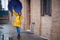 A young handsome woman in a yellow raincoat and with umbrella is having a phone call while walking the city on a rainy day. Walk, Royalty Free Stock Photo