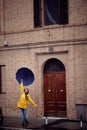 A young handsome woman in a yellow raincoat and with umbrella is posing for a photo while walking the city on a rainy day. Walk, Royalty Free Stock Photo