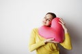 Young handsome woman in yellow tshirt holding big plush red heart over empty white background.Lifestyle and Holiday Royalty Free Stock Photo