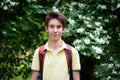 Young handsome 15 years old teen boy wearing yellow t-shirt with backpack looking at camera and happy smiling, summer park outdoor Royalty Free Stock Photo