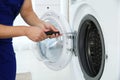 Young handyman fixing washing machine, closeup.