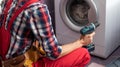 Young handyman fixing washing machine, closeup. Laundry day. Royalty Free Stock Photo