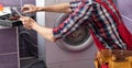 Young handyman fixing washing machine, closeup. Laundry day. Royalty Free Stock Photo