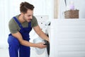 Young handyman fixing washing machine at home. Royalty Free Stock Photo