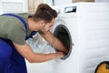 Young handyman fixing washing machine at home. Royalty Free Stock Photo