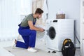 Young handyman fixing washing machine at home. Royalty Free Stock Photo