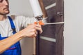 Young handyman installing door with an mounting foam in a room