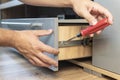 The man adjusts the drawer. Self-assembly of furniture. Young Handyman In Overall Installing Drawer In Kitchen