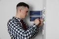 Young handyman with screwdriver repairing electrical panel board indoors Royalty Free Stock Photo