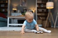 Young happy adorable baby girl or boy sitting on the floor of apartment playing with his or her favorite toy. Cute child crawling Royalty Free Stock Photo