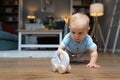 Young happy adorable baby girl or boy sitting on the floor of apartment playing with his or her favorite toy. Cute child crawling Royalty Free Stock Photo